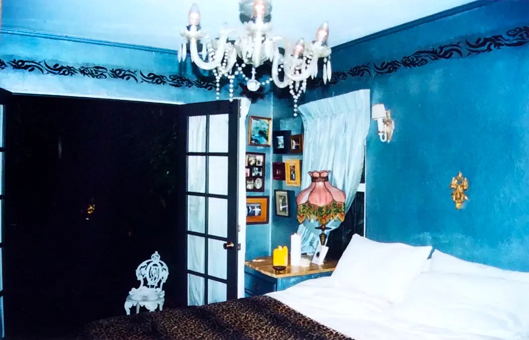 Cozy bedroom with blue walls and a chandelier.