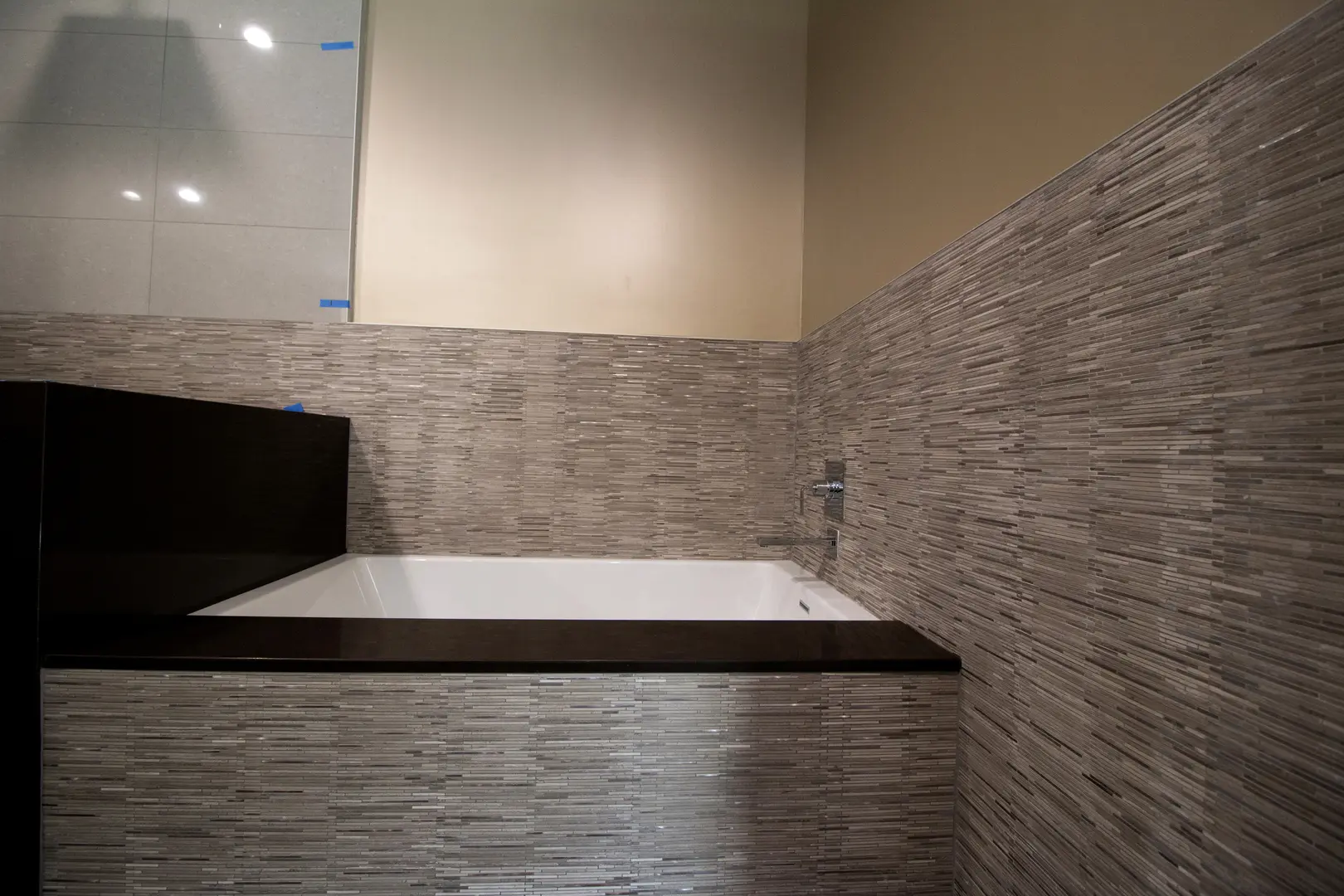 Modern bathroom corner with a large mirror and stone-textured walls.