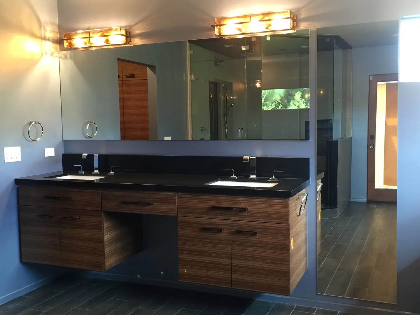 Modern bathroom with wooden vanity and large mirror.