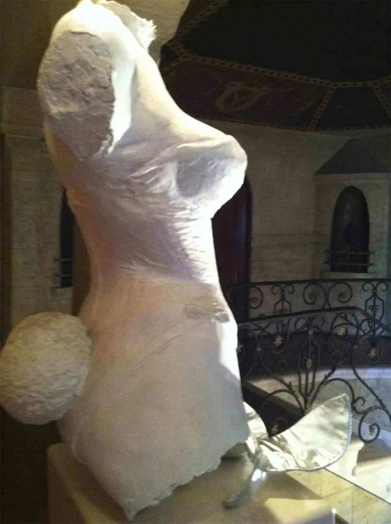 Sculpture of a woman with a spherical element behind her.