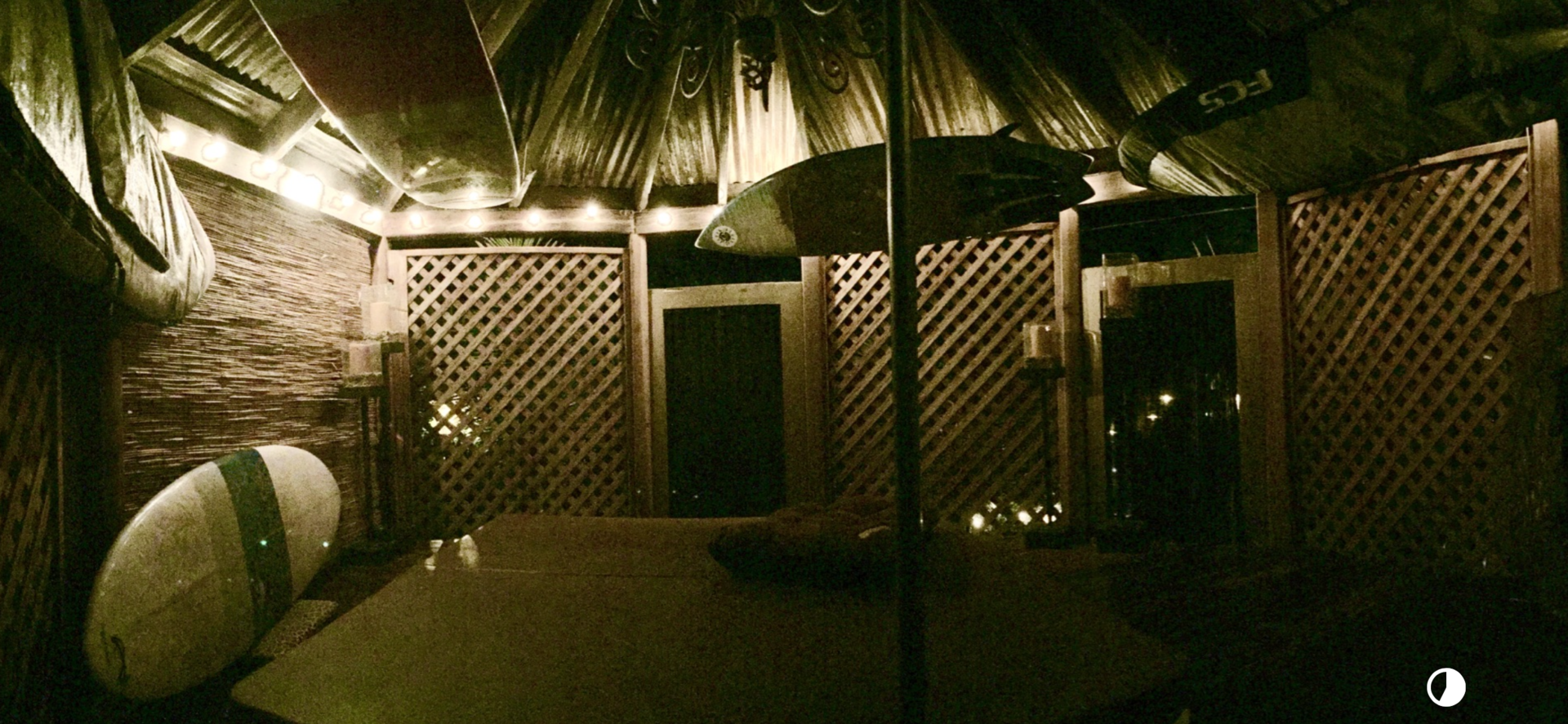 Dimly lit outdoor seating area with wooden lattice walls and string lights.