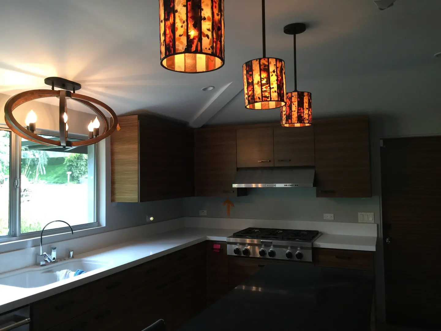 Modern kitchen with pendant lighting and dark wood cabinets.