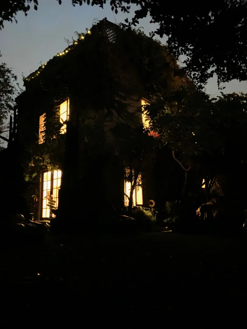 A dark house glowing warmly from lit windows at night.