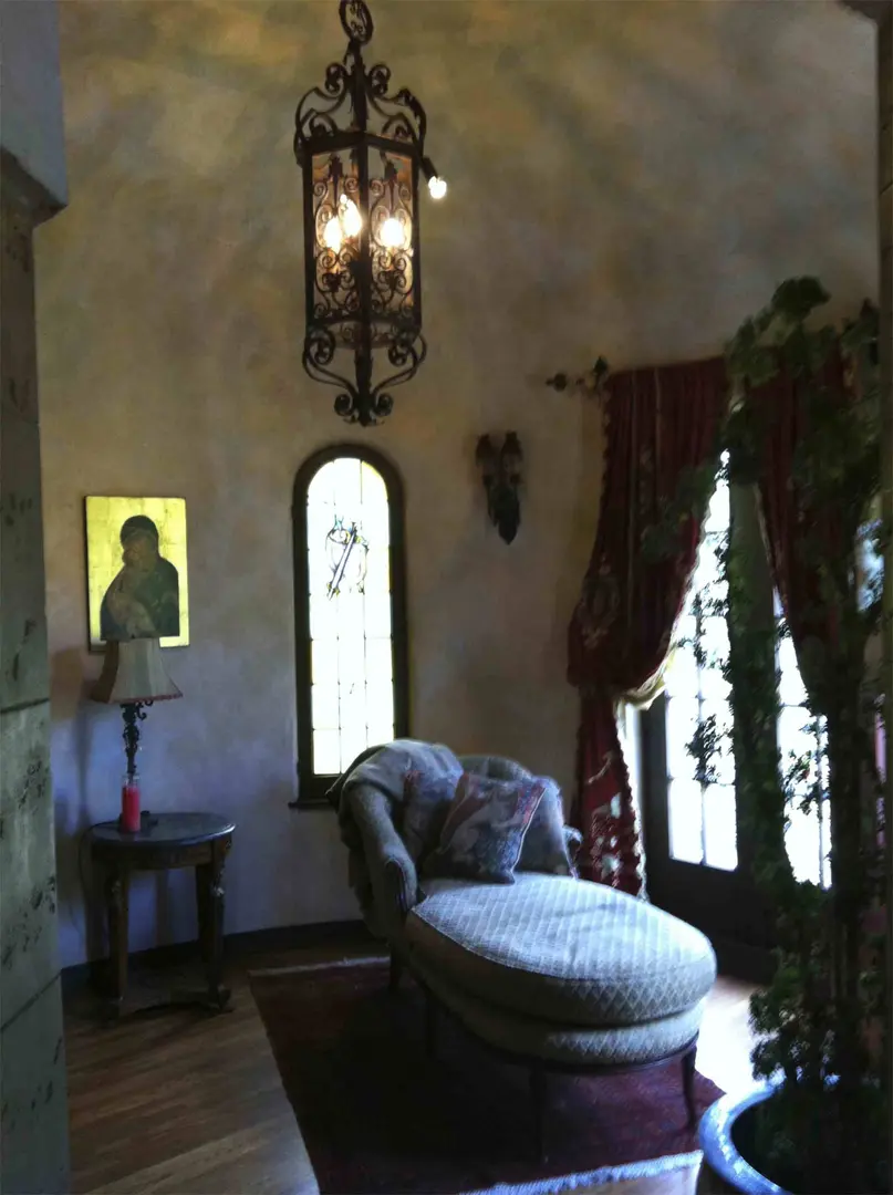 Cozy room with a chaise lounge, warm lighting, and arched windows.