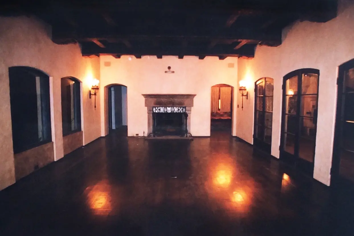 Empty room with wooden ceiling beams and a fireplace.