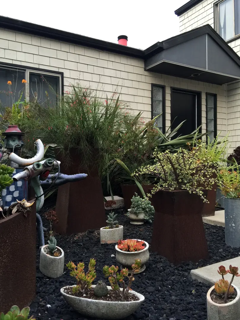 A quaint garden with potted plants outside a small house.