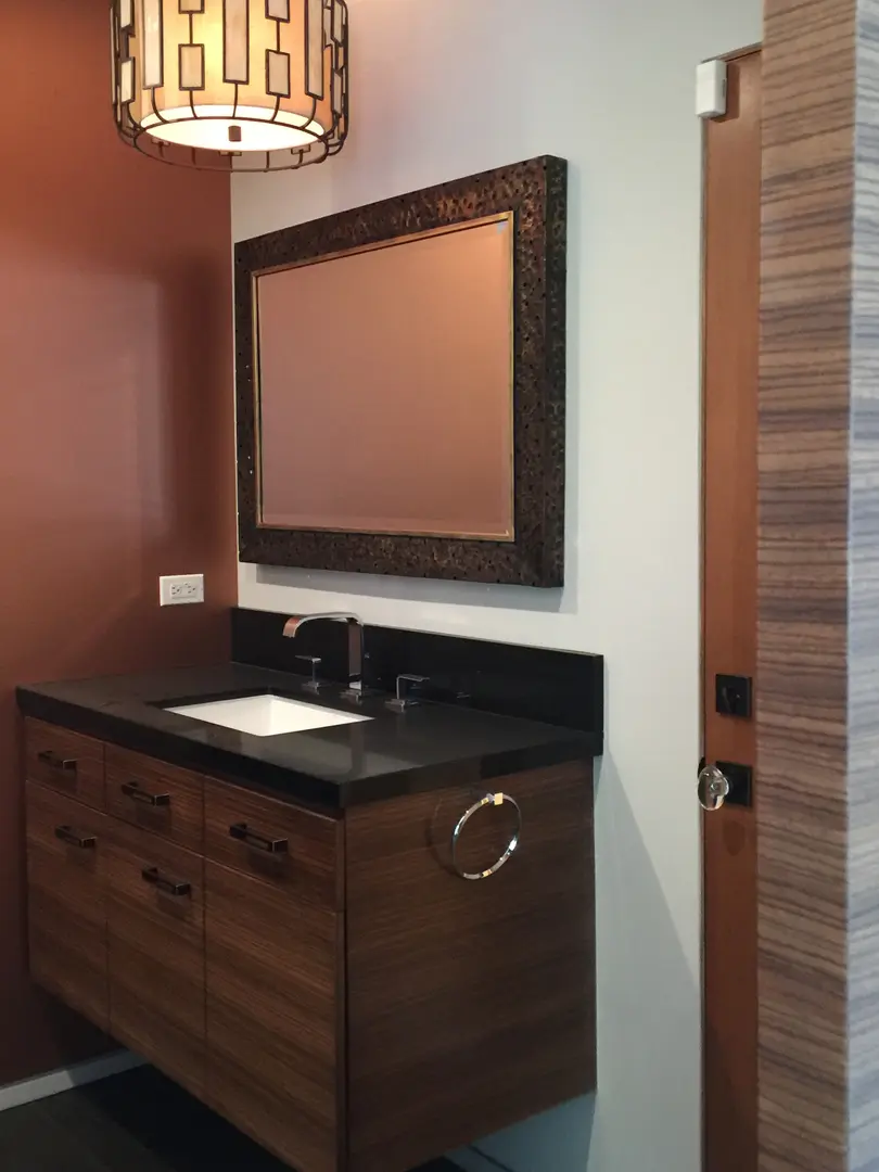 Modern bathroom vanity with a large framed mirror and wooden cabinets.