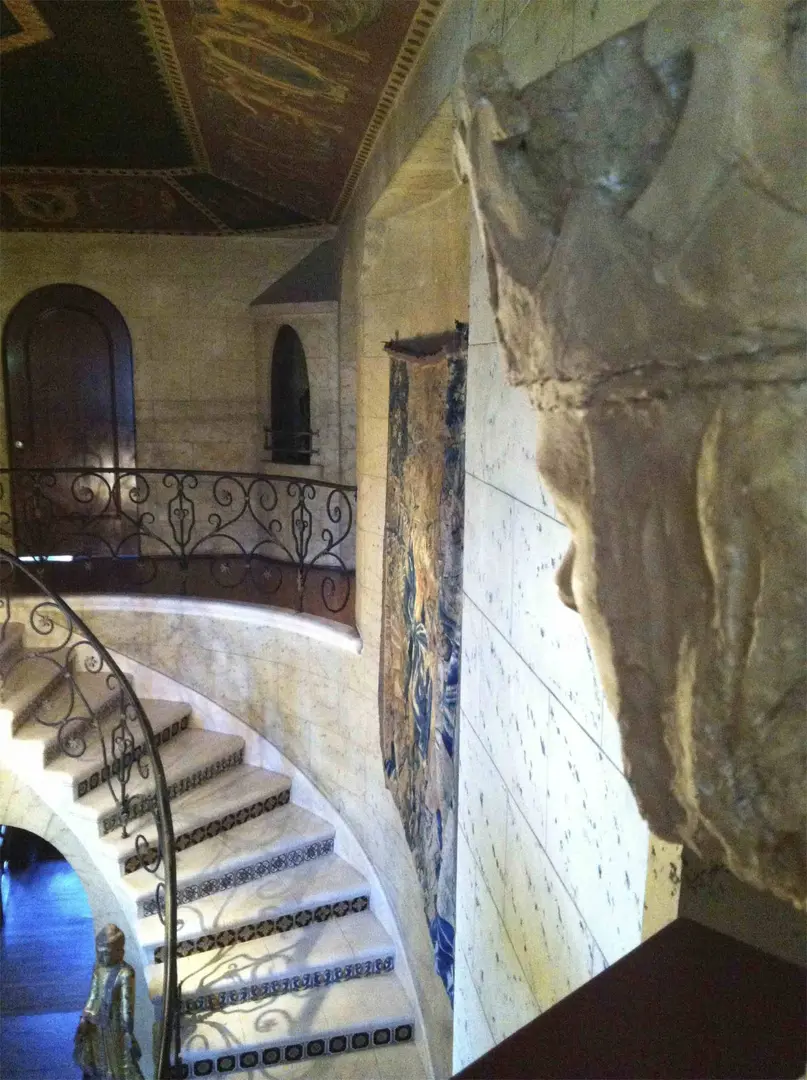 Curved staircase with wrought iron railing and stone walls.