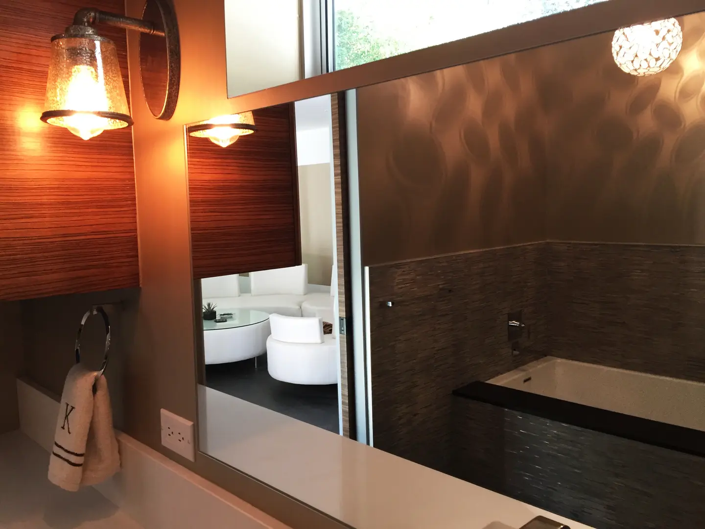 Modern bathroom with large mirror and stylish lighting fixtures.
