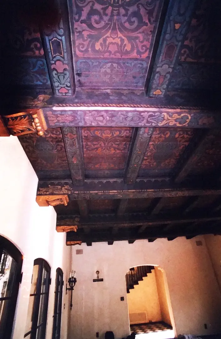 Intricately painted wooden ceiling beams in a historic room.