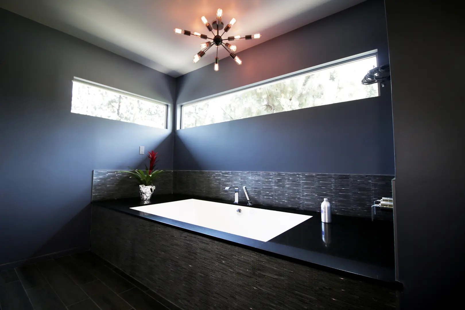 Modern bathroom with sleek black design and large bathtub.