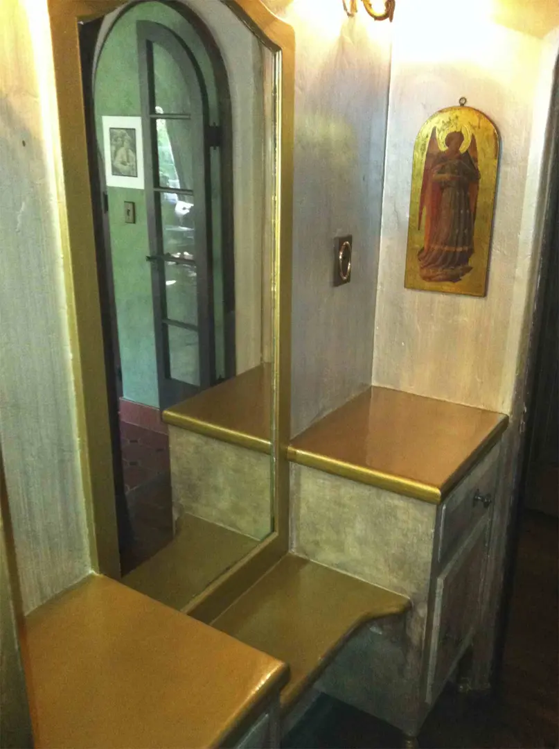 Small dressing area with mirror and wooden bench.