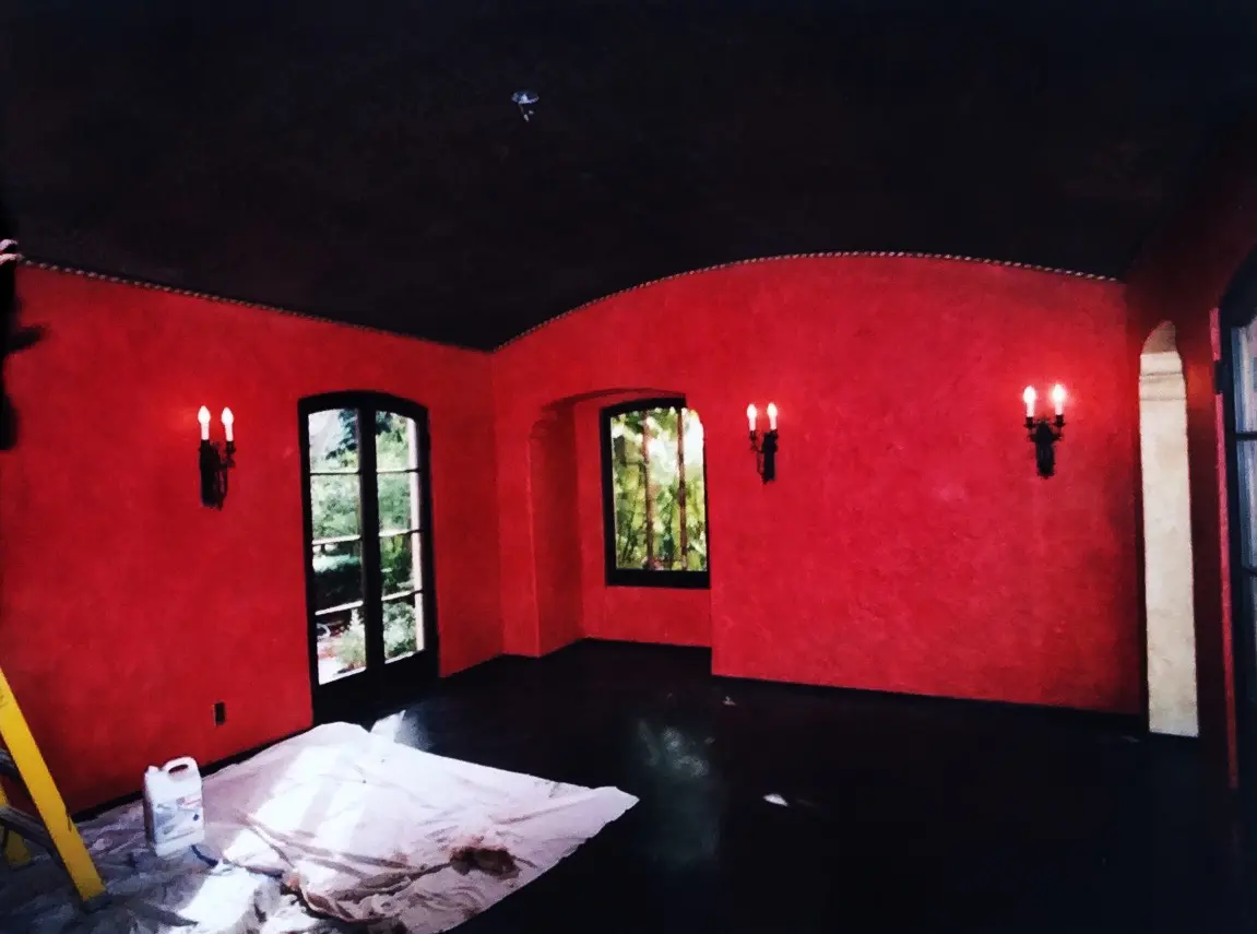 Red-walled room with black floor, windows, and sconces.